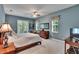 Bright bedroom featuring French doors leading to an outdoor balcony, ceiling fan, and light blue walls at 16420 Iola Woods Trl, Dade City, FL 33523