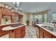 Spacious kitchen with an island cooktop, counter seating, wooden cabinets, and dining area by sun-filled windows at 16420 Iola Woods Trl, Dade City, FL 33523