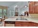 Bright kitchen featuring stainless steel sink, wood cabinets, and view of a living room with a fireplace at 16420 Iola Woods Trl, Dade City, FL 33523