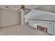 Spacious upstairs loft with railing overlooking the living area, plus neutral carpet and ceiling fan at 16420 Iola Woods Trl, Dade City, FL 33523