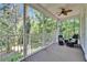 Relaxing screened porch features a ceiling fan and outdoor furniture overlooking the wooded backyard at 16420 Iola Woods Trl, Dade City, FL 33523