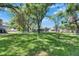 A spacious backyard with lush green grass, shade trees, and a small deck, all under a clear blue sky at 1806 Chickasaw Trl, Valrico, FL 33596