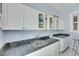 Bar with gray granite countertops, white cabinetry, storage, and a convenient sink for entertaining at 1806 Chickasaw Trl, Valrico, FL 33596