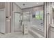 A large bathroom with a corner tub, a glass shower, white tile floor and striped wallpaper at 1806 Chickasaw Trl, Valrico, FL 33596