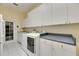 An organized laundry room with a washer, dryer, sink, white cabinetry, and countertop space at 1806 Chickasaw Trl, Valrico, FL 33596