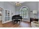 Cozy living room with a grand piano, chandelier, and a view through glass doors at 1806 Chickasaw Trl, Valrico, FL 33596