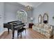 Elegant living room featuring a grand piano, chandelier, and large arched window at 1806 Chickasaw Trl, Valrico, FL 33596