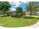 Well-manicured lawn showcasing an exterior elevation with arched window, bushes, and a driveway at 27054 Fordham Dr, Wesley Chapel, FL 33543