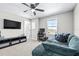 Well-lit bedroom featuring a ceiling fan, TV, workstation and comfortable blue corduroy couch at 31966 Asbury Ave, Wesley Chapel, FL 33545