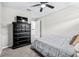 Carpeted bedroom with ceiling fan, large black dresser, and an entrance to the hallway at 31966 Asbury Ave, Wesley Chapel, FL 33545