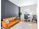 Stylish living room featuring a tan leather sofa, dark accent wall, and bright workspace with a modern desk and computer at 31966 Asbury Ave, Wesley Chapel, FL 33545