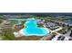 Expansive aerial view of a community lagoon with white sandy beach, recreational facilities, and surrounding modern homes at 32046 Powderpuff Mimosa Dr, San Antonio, FL 33576