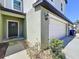 Close-up of a two-story townhome featuring a garage door, front door, lush landscaping, and neutral color palette at 32046 Powderpuff Mimosa Dr, San Antonio, FL 33576