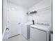 Clean laundry room with white washer, dryer, shelving, and tile flooring at 32046 Powderpuff Mimosa Dr, San Antonio, FL 33576