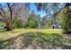 Expansive front yard of home with mature trees, green grass, and a storage shed in the background at 4041 Lane Rd, Zephyrhills, FL 33541