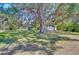 Expansive front yard featuring mature trees, a small shed, and a glimpse of the charming home beyond at 4041 Lane Rd, Zephyrhills, FL 33541