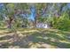 Spacious front yard of home with lush trees providing ample shade and a storage shed at 4041 Lane Rd, Zephyrhills, FL 33541