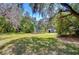 Expansive front yard of home with mature trees, green grass, and a storage shed in the background at 4041 Lane Rd, Zephyrhills, FL 33541