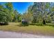 Beautiful front yard featuring green grass, a storage shed, and mature trees, creating a park-like setting at 4041 Lane Rd, Zephyrhills, FL 33541