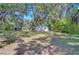 Spacious front yard of home with mature trees providing ample shade and a storage shed at 4041 Lane Rd, Zephyrhills, FL 33541