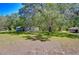 Spacious front yard with shade trees, a shed, and a covered parking area providing functionality and curb appeal at 4041 Lane Rd, Zephyrhills, FL 33541