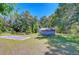 View of concrete slab and shed in large shady front yard with mature trees and green grass at 4041 Lane Rd, Zephyrhills, FL 33541