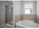 Well-lit bathroom featuring a glass shower and a soaking tub under a window with adjustable blinds at 424 Bahama Grande Blvd, Apollo Beach, FL 33572