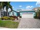 Charming, single-story home features lush landscaping, two-car garage, and a welcoming, light blue exterior at 424 Bahama Grande Blvd, Apollo Beach, FL 33572