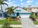 Charming home features lush landscaping, two-car garage, and a welcoming, light blue exterior and paver driveway at 424 Bahama Grande Blvd, Apollo Beach, FL 33572