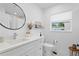 Contemporary bathroom with a round mirror, white vanity, and a decorative shelf with stylish accents at 5298 Oxford N Ave, St Petersburg, FL 33710