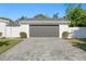A detached two-car garage features a gray door and a paver driveway, complemented by manicured landscaping and white perimeter fences at 5298 Oxford N Ave, St Petersburg, FL 33710