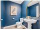 Stylish half bathroom features a pedestal sink, gold framed mirror, and vibrant blue walls at 5429 Companion Ln, Tampa, FL 33619