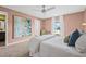 Bright bedroom featuring a ceiling fan, carpet, and art to complement the warm pink tone of the walls at 5429 Companion Ln, Tampa, FL 33619