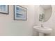 Neat powder room includes pedestal sink, and tastefully decorated with beach themed artwork and decor at 6915 Broad River Ave, Land O Lakes, FL 34638