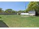 Spacious backyard featuring a storage shed, green grass, and a white brick wall at 747 Stillview Cir, Brandon, FL 33510
