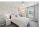 Charming bedroom featuring a decorative wallpaper accent wall, a ceiling fan, and a soft color palette at 7591 Cypress Walk Dr, New Port Richey, FL 34655