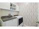 Modern laundry room featuring a new washer and dryer, built-in storage, and stylish wallpaper at 7591 Cypress Walk Dr, New Port Richey, FL 34655