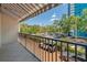 A tiled balcony with black railing, offers a view of parking and mature trees under a striped awning at 105 4Th Ne Ave # 220, St Petersburg, FL 33701