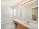 Bathroom features a soaking tub with tile surround, a large mirror, a sink, and a window for natural light at 10534 Collar Dr, San Antonio, FL 33576