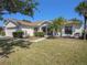 Single-story home with lush green lawn, mature palm trees, and screened entry at 10534 Collar Dr, San Antonio, FL 33576