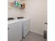 Convenient laundry room with washer, dryer, shelving, and tile floors at 1304 Tahitian Sunrise Dr, Plant City, FL 33565