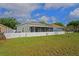 Spacious backyard, with well-maintained green grass, white vinyl fence and enclosed screened in patio at 13131 Early Run Ln, Riverview, FL 33578