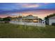 Picture perfect evening view of the backyard with an enclosed screened-in patio, a white fence and green grass at 13131 Early Run Ln, Riverview, FL 33578