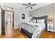 Bright bedroom with hardwood floors, patterned wall, ceiling fan, and a comfortable-looking gray bed at 2081 Pointe Alexis Dr, Tarpon Springs, FL 34689