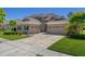 Beautiful home with a brick paver driveway, lush green lawn, and a spacious three-car garage at 27318 Sora Blvd, Wesley Chapel, FL 33544