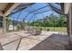 Screened patio with stone floors, seating, and a view of the landscaped backyard at 27318 Sora Blvd, Wesley Chapel, FL 33544
