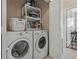 Laundry room with a side by side washer and dryer and storage shelving above at 2746 Via Tivoli # 135A, Clearwater, FL 33764