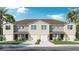 Beautiful townhome exterior with a two-car garage, tan paint, well-kept lawn, and tropical landscaping at 31280 Paper Birch St, Wesley Chapel, FL 33545