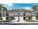 Beautiful townhome exterior with a two-car garage, neutral paint, well-kept lawn, and tropical landscaping at 31280 Paper Birch St, Wesley Chapel, FL 33545