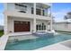 Back of home shows two levels, outdoor seating on balconies, large brown garage door, and attached pool/spa at 326 129Th E Ave, Madeira Beach, FL 33708